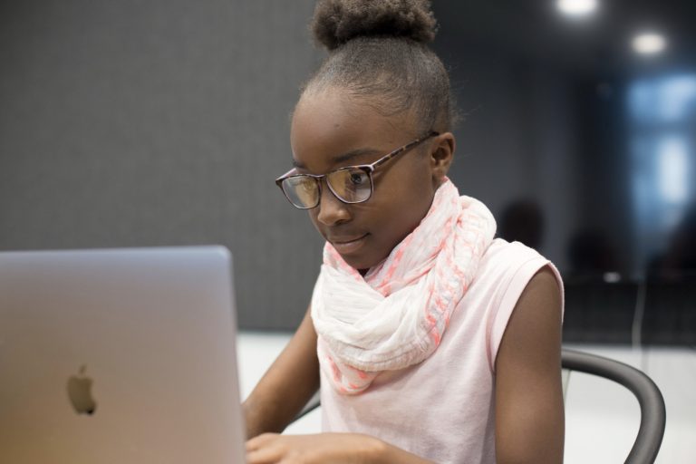 a young Black girl typing on a laptop