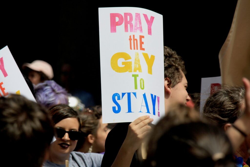 someone holds a sign that says 'pray the gay to stay'